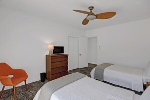 A hotel room with two beds, a ceiling fan, a TV on a wooden dresser, and a leopard print carpet. - Garden Villas Paradise (Palm Springs)