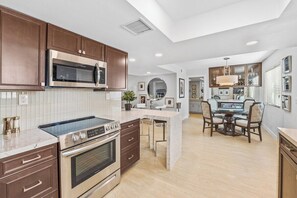 A modern kitchen with a central island, built-in microwave, and stainless steel appliances. - The Ricardo on Ramon (Palm Springs)