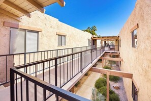 A building with a covered walkway, outdoor seating area, and a clear sky. - The Ricardo on Ramon (Palm Springs)