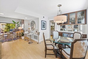 A modern living room with a glass dining table, comfortable seating, and a large window. - The Ricardo on Ramon (Palm Springs)