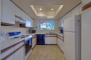 A compact kitchen with a stove, microwave, dishwasher, and refrigerator. - Mesquite Getaway - 2BR Condo with Pool and Views (Palm Springs)
