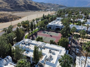A residential area with a tennis court, surrounded by palm trees and a hilly landscape. - Casa Palm Canyon - South PS (Palm Springs)