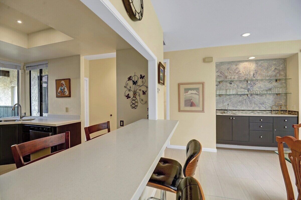A modern kitchen with a central island, dark cabinetry, and decorative wall art.