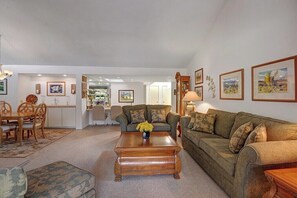 A living room with a sofa set, a coffee table with flowers, and framed artwork on the walls. - Palm Springs Waterfront Oasis (Palm Springs)