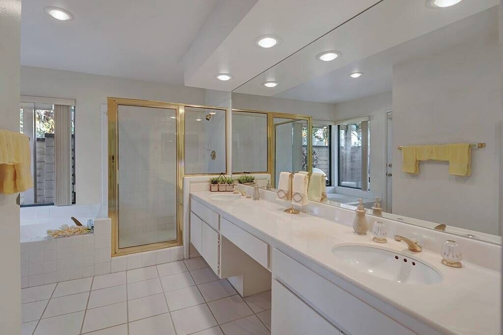 A modern bathroom with a large mirror, two sinks, and a shower enclosure.