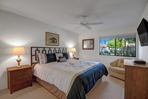 A bedroom with a bed, bedside tables, a ceiling fan, a window with a view, and a TV mounted on the wall. - Palm Springs Waterfront Oasis (Palm Springs)