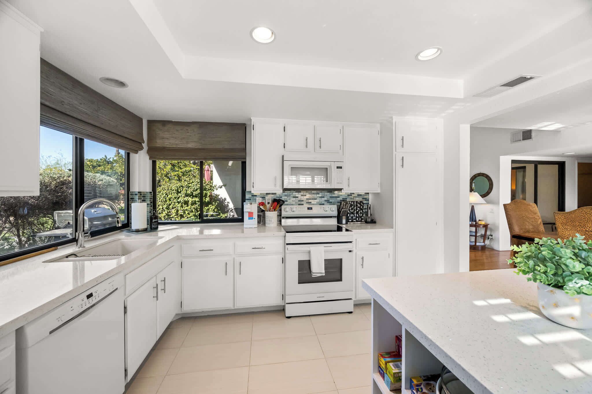 A modern kitchen with white cabinetry, a built-in oven, and a microwave.