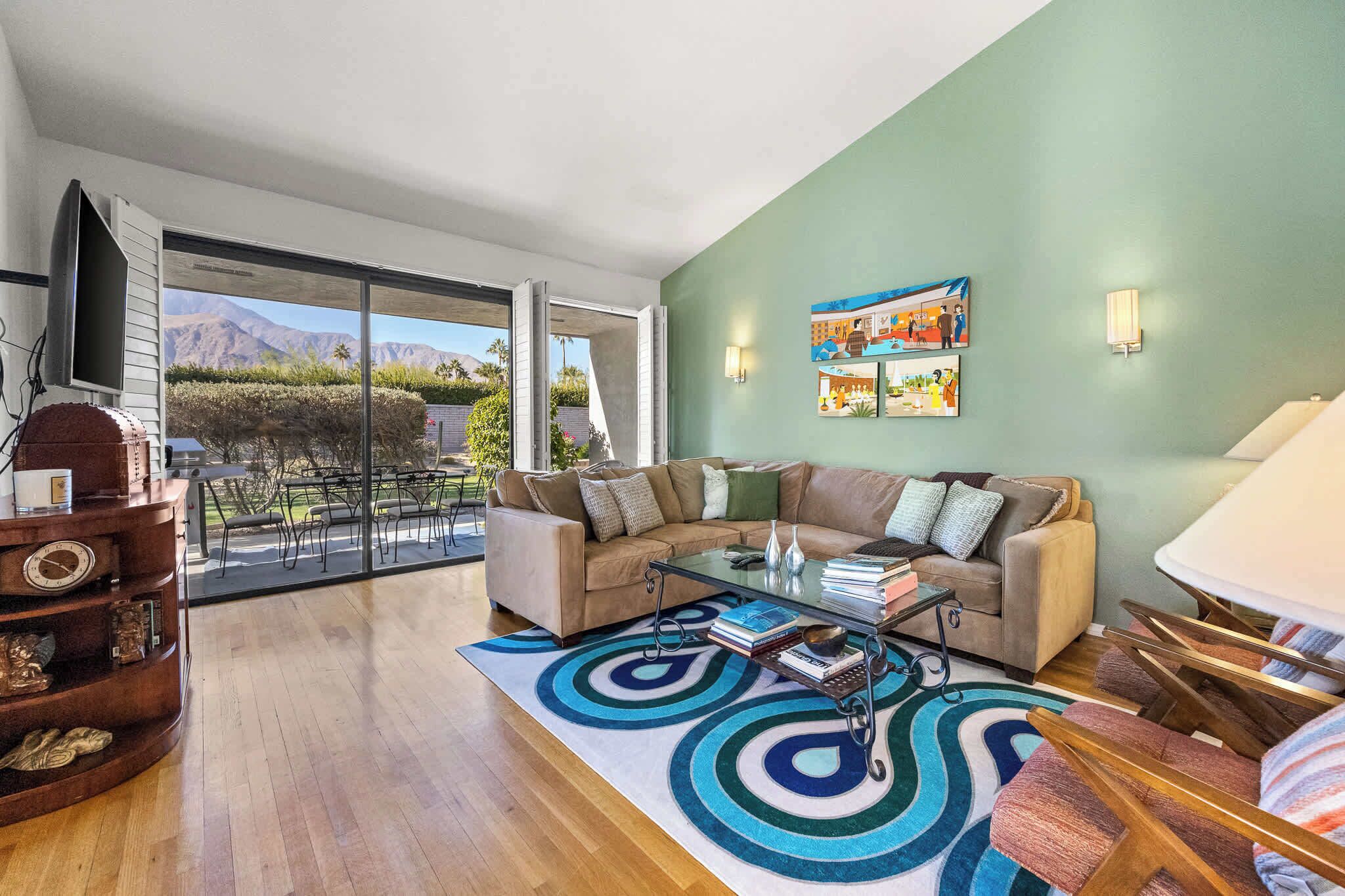 A living room with a sofa, coffee table, and a view of mountains through a sliding door.