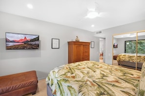 Une chambre à coucher comprenant un lit, une armoire en bois, un banc et un grand miroir.