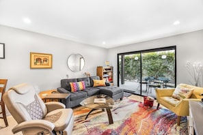A modern living room with a sectional sofa, a glass coffee table, and a vibrant rug. - Estados Sanctuary - South Palm Springs (Palm Springs)