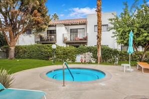 A swimming pool with a metal ladder, surrounded by a concrete deck, with a building in the background. - Estados Sanctuary - South Palm Springs (Palm Springs)