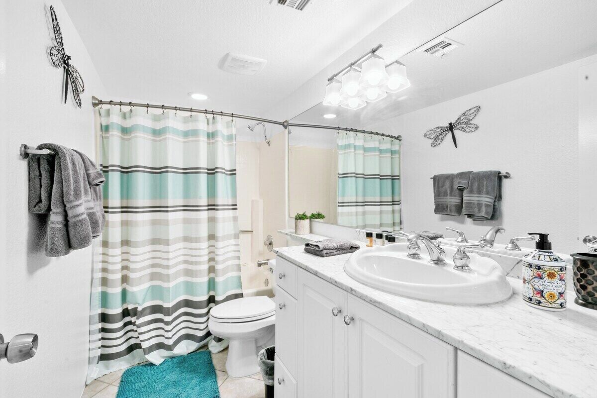A bathroom with a white sink, two faucets, a mirror, and a striped shower curtain.