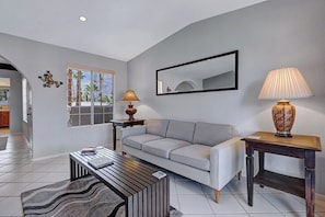 A modern living room with a sofa, coffee table, lamps, and a large window. - The Mesquite Mesmeric (Palm Springs)