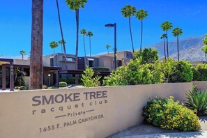 Ein privater Tennisclub namens Smoke Tree mit freiem Blick auf die Umgebung, darunter Palmen und ein Berg im Hintergrund.
