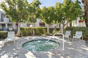 A hot tub with a metal railing, surrounded by trees and white lounge chairs. - La Palme Urban Chic Palm Springs Condo (Palm Springs)