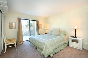 A bedroom with a bed, a chair, a nightstand, and a window with curtains. - - Ranch Club Getaway - (Palm Springs)