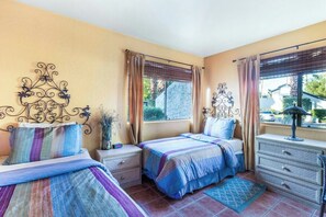 Ein Schlafzimmer mit zwei Betten, einem Nachttisch, einer Kommode und einem Fenster mit Vorhängen.