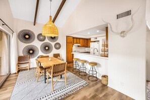 A modern kitchen with wooden cabinets, a white countertop, and a hanging light fixture. - Araby Luxe by Design (Palm Springs)