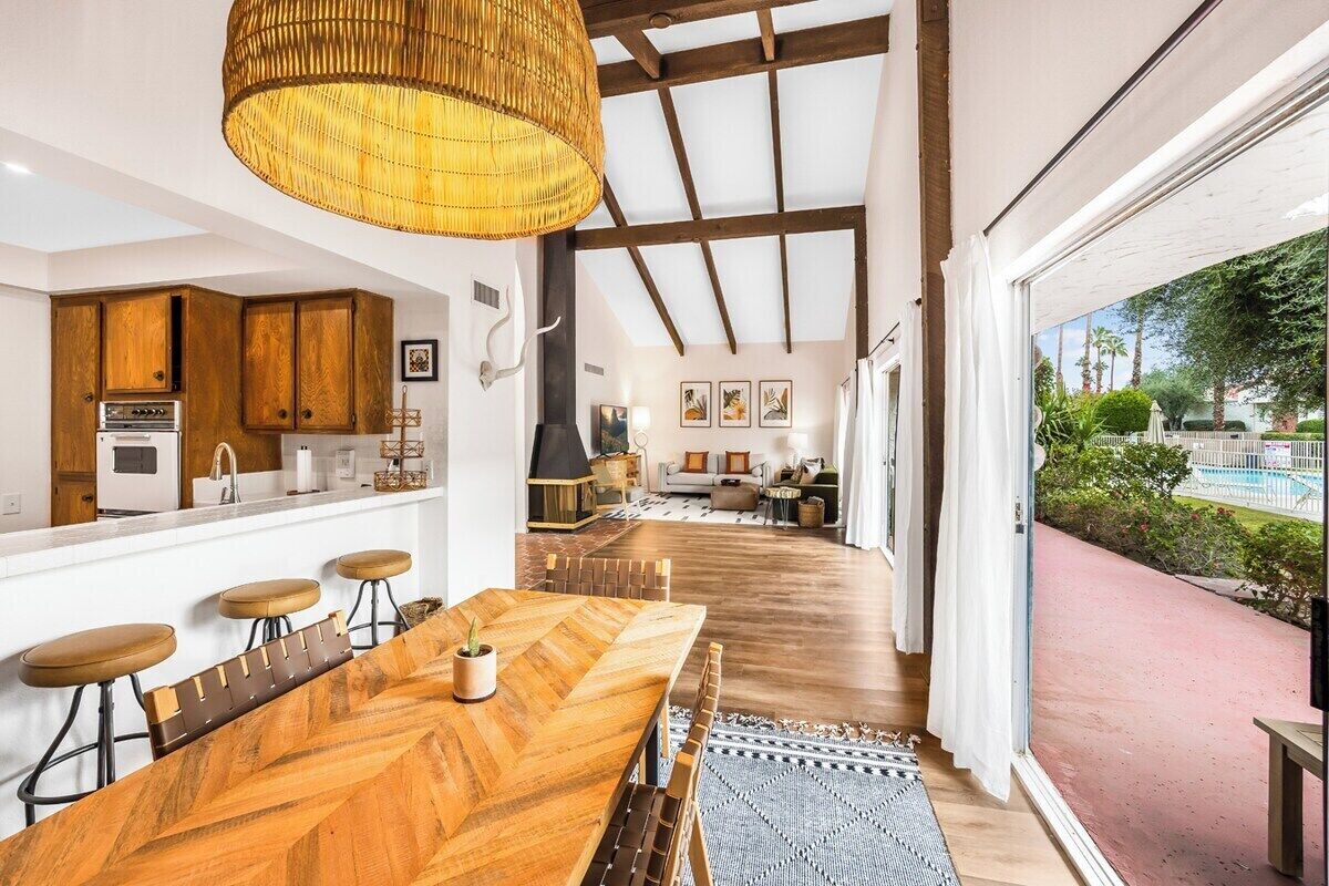 Una cucina moderna con mobili in legno, un ampio tavolo da pranzo in legno e un lampadario.