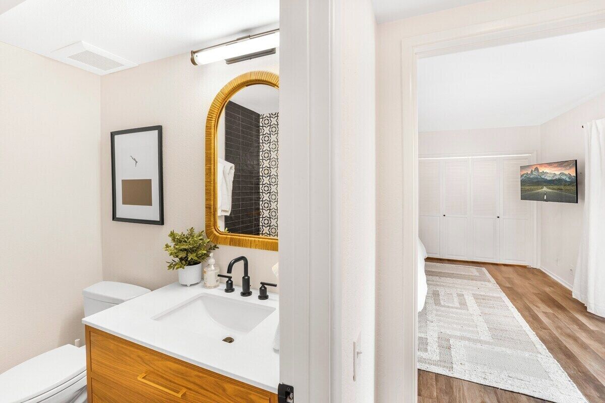 Een moderne badkamer met een witte wastafel, een houten opbergmeubel en een grote spiegel.