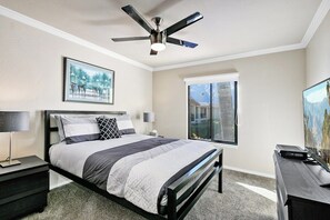 Ein Schlafzimmer mit einem Bett, einem Deckenventilator, einem Fenster und einem Fernseher.