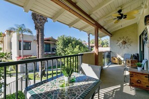 Ein überdachter Balkon mit Tisch, Stühlen und Deckenventilator.