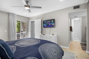 A bedroom with a bed, a television mounted on the wall, and a ceiling fan. - Biltmore Gem - South Palm Springs (Palm Springs)