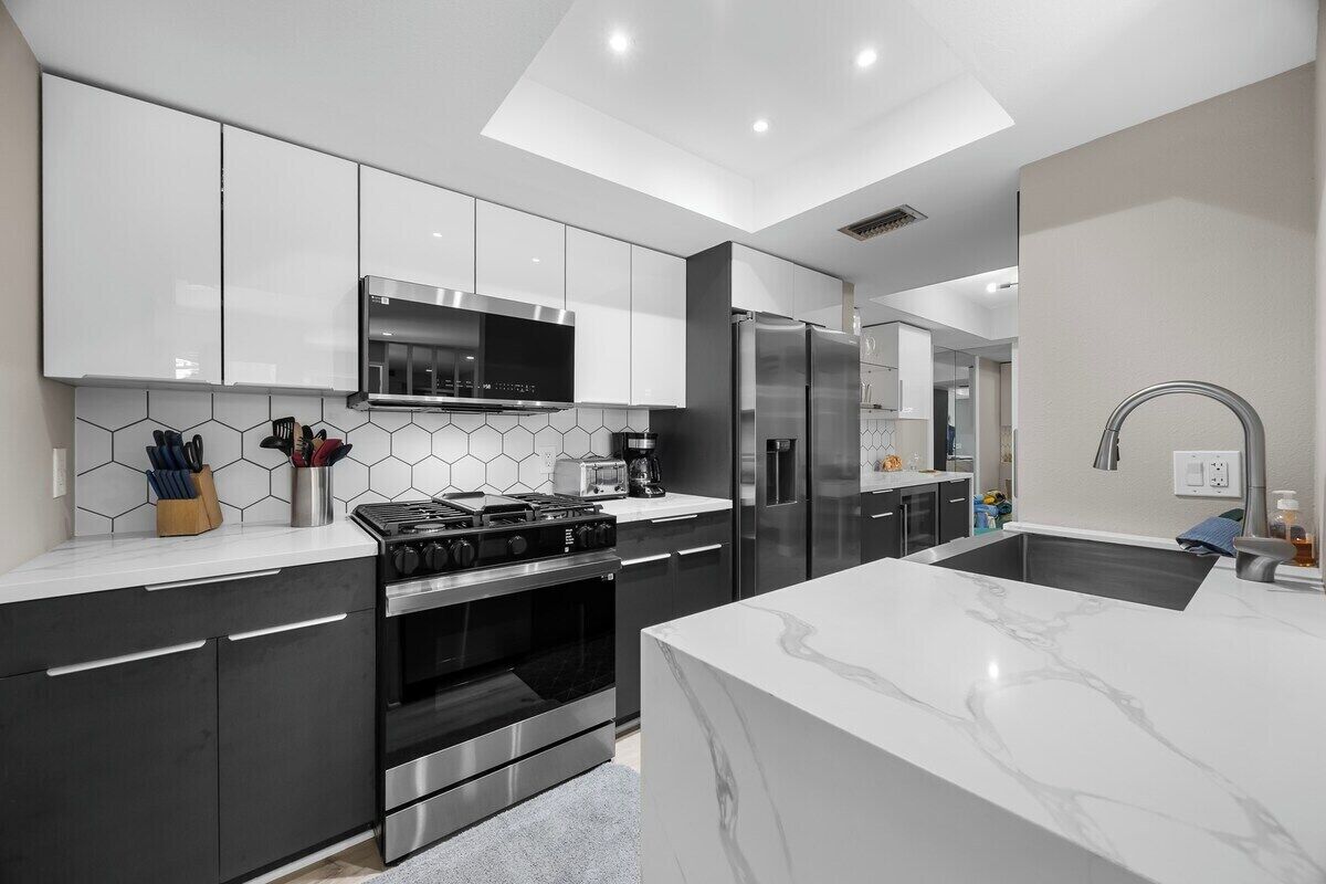 Een moderne keuken met een centraal eiland, ingebouwde apparatuur en een backsplash van hexagonale tegels.