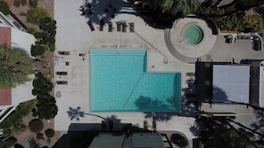An aerial view of a swimming pool area with lounge chairs, a hot tub, and surrounding landscaping. - Biltmore Gem - South Palm Springs (Palm Springs)