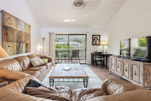 A living room with a sofa, a coffee table, a TV, and a dining area with chairs and a table. - Canyon Granada Getaway (Palm Springs)