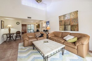 A living room with a sofa, coffee table, and a painting on the wall. - Canyon Granada Getaway (Palm Springs)