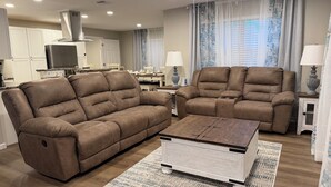 A living room with two brown sofas, a coffee table, and a TV in the background. - 4 Bedroom Coastal Farmhouse In Cocoa Florida (Cocoa)