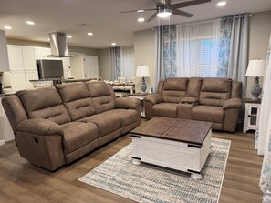 A living room with two brown sofas, a coffee table, and a TV in the background. - 4 Bedroom Coastal Farmhouse In Cocoa Florida (Cocoa)