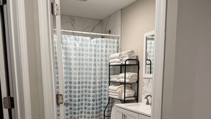 A bathroom with a toilet, a sink, a towel rack, and a shower curtain. - 4 Bedroom Coastal Farmhouse In Cocoa Florida (Cocoa)