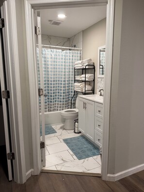 A bathroom with a toilet, a sink, a towel rack, and a shower curtain. - 4 Bedroom Coastal Farmhouse In Cocoa Florida (Cocoa)