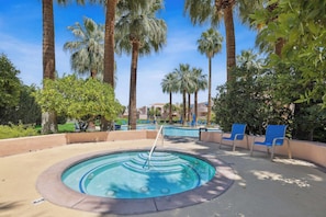A swimming pool with a hot tub, surrounded by palm trees and blue lounge chairs. - Deauville Amora - Downtown PS (Palm Springs)
