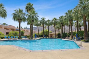 A swimming pool with palm trees, lounge chairs, and a desert landscape in the background. - Deauville Amora - Downtown PS (Palm Springs)
