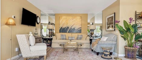 Un salon avec un canapé, des fauteuils, une table basse et un téléviseur.