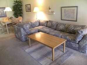 Ein Wohnzimmer mit einer Couch, einem Couchtisch, einer Lampe und einer Pflanze.
