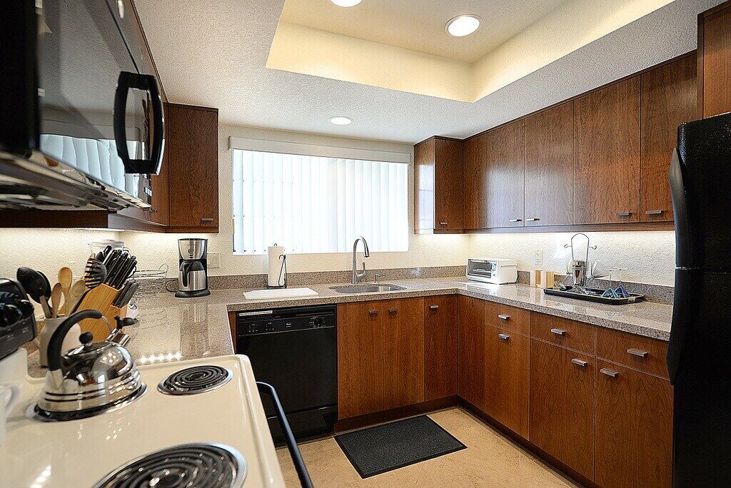 A compact kitchen with wooden cabinets, a dishwasher, and a stove.