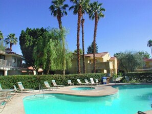 A swimming pool with lounge chairs, palm trees, and a building with a red-tiled roof. - Mesquite Tranquility Phase 3 (Palm Springs)