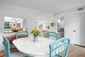 A dining area with a round table, four chairs, and a vase of flowers. - Midtown Mountain View Villa (Palm Springs)