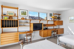 A compact room with a bed, a desk, a chair, and a television. - Midtown Mountain View Villa (Palm Springs)