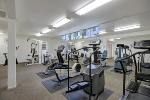 Ett gym med olika typer av träningsutrustning, inklusive löpband och styrketräningsmaskiner, samt en vägg med speglar.