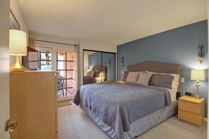 Ein Schlafzimmer mit Bett, Nachttischen, einer Lampe, einem Spiegel und Blick ins Freie.