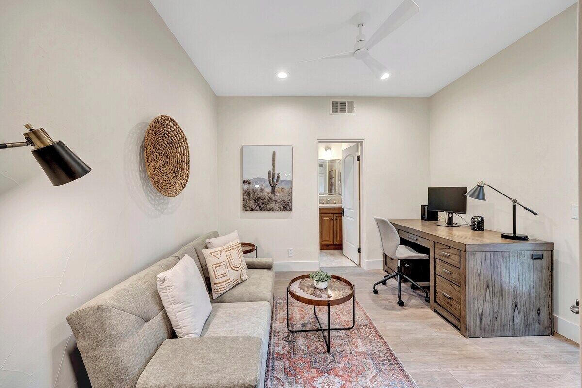 Un salon moderne avec un canapé, une table basse et un bureau avec un ordinateur.