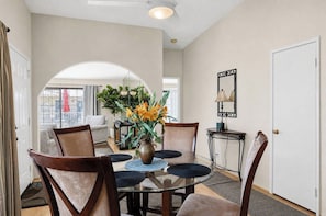 A dining area with a glass table, chairs, a vase with flowers, and a mirror on the wall. - Mesquite Serenity Phase 4 (Palm Springs)