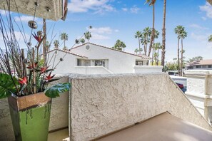 A balcony with a view of palm trees and a building in the background. - Mesquite Breeze Phase 1 (Palm Springs)