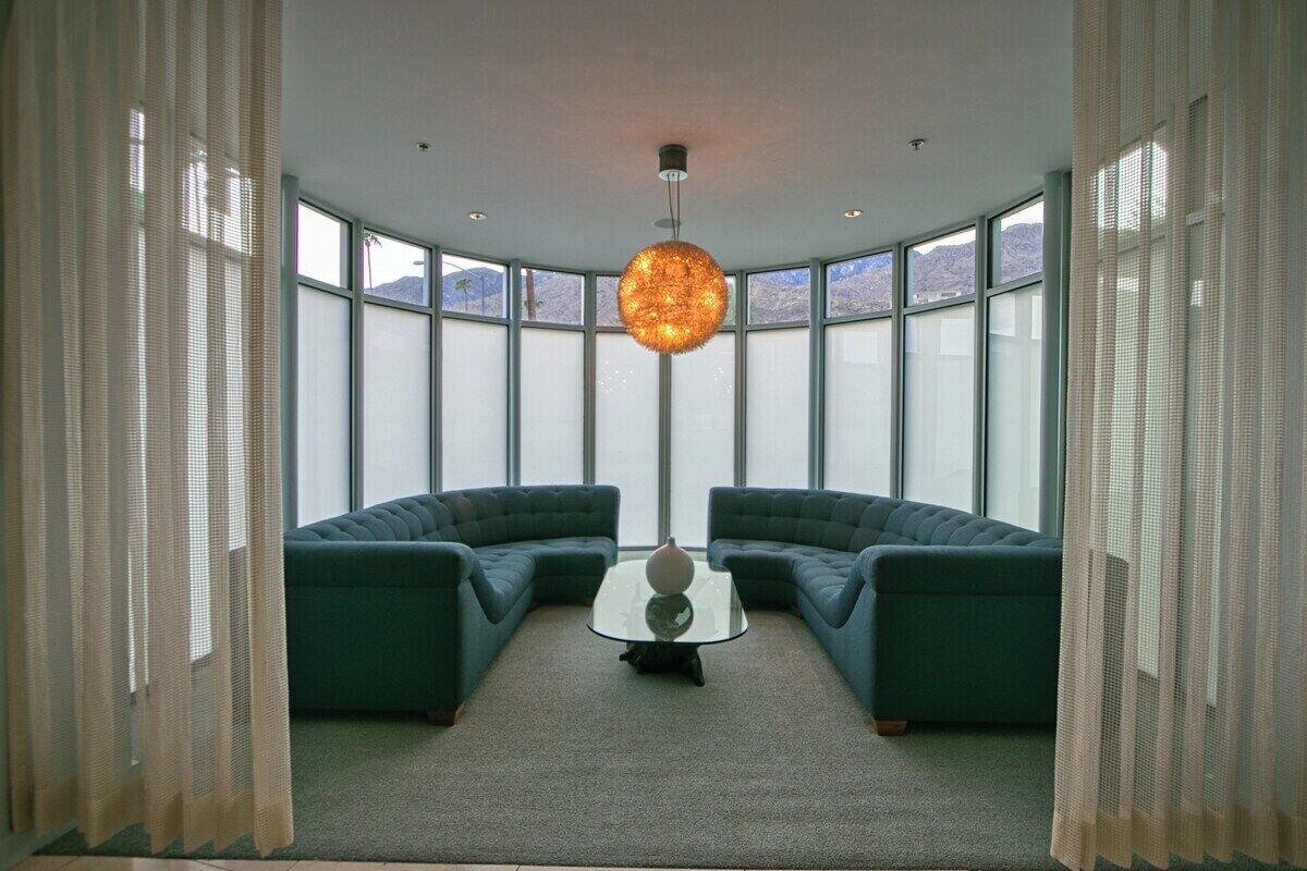 A room with a curved layout, large windows, and a central round table.