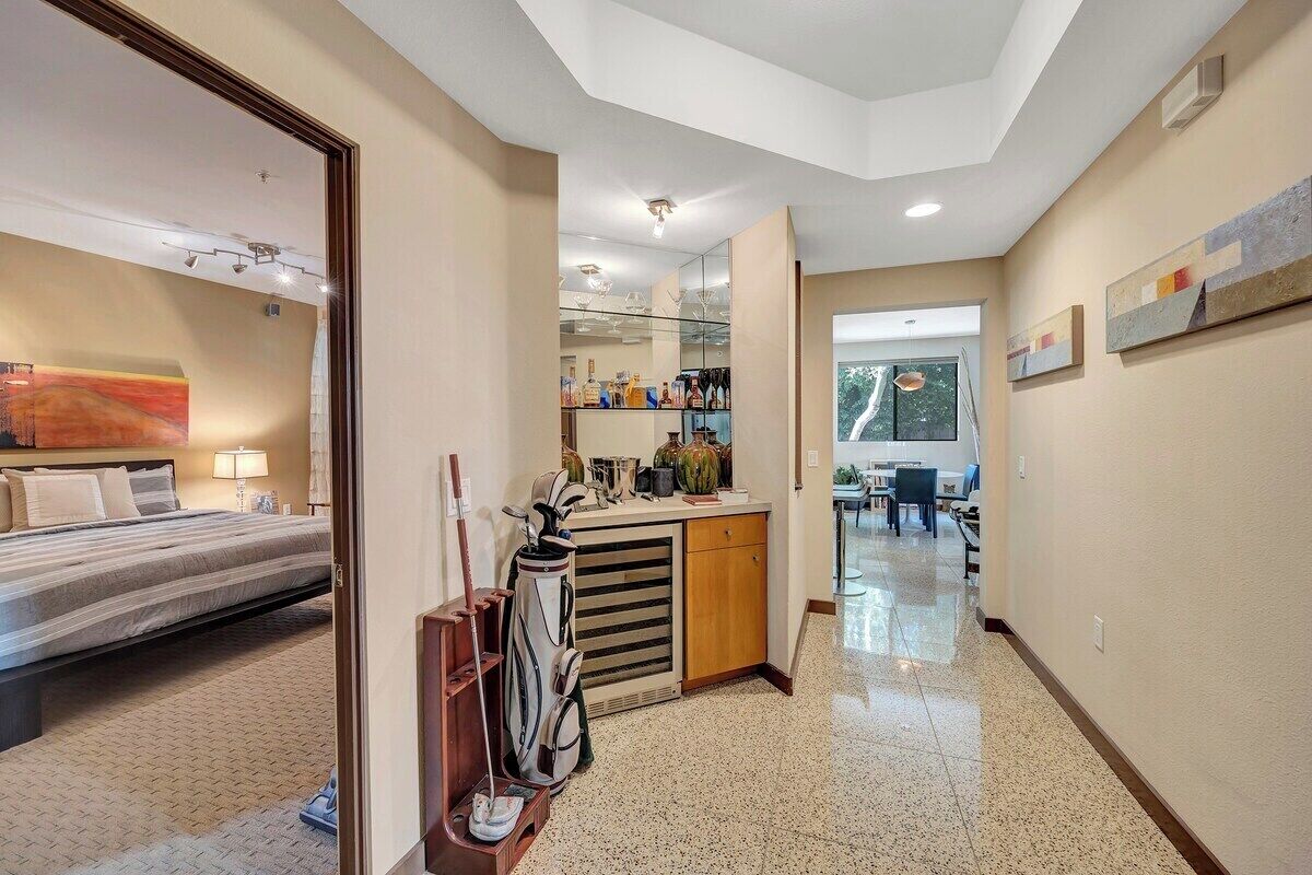 A hotel room with a bed, a desk, a mirror, and a kitchenette.